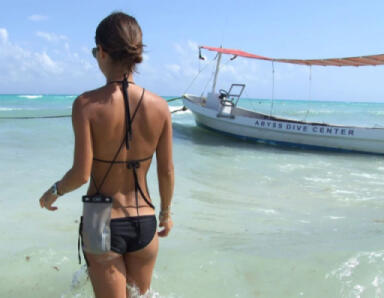 A lady walking on a sandy beach using the OverBoard Dry Phone case.